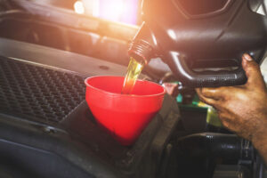 A mechanic pours oil into a vehicle